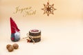 Christmas postcard with text Joyeux Noel and a beige background, nuts, wooden candle and a funny gnome