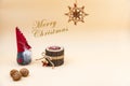 Christmas postcard with text Merry Christmas and a beige background, nuts, wooden candle and a funny gnome