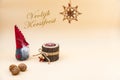 Christmas postcard with text Vrolijk Kerstfeest and a beige background, nuts, wooden candle and a funny gnome