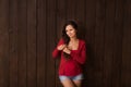 Christmas pregnant woman in jeans shorts and red top holds hands on belly on a dark brown background. Pregnancy, maternity, expect Royalty Free Stock Photo