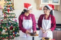 Christmas Preparation And Celebration Concept, Two Young Girls Wearing Apron And Santa Hat looking at each other Making Cake Bread Royalty Free Stock Photo