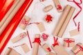 Christmas preparations background - wrapping paper, gift boxes, red ribbon and bows, twine as festive pattern on white wood board. Royalty Free Stock Photo