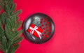 Christmas present, star confetti on a black plate, green spruce on a red background Royalty Free Stock Photo