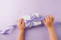 Christmas present stylish gift box in kids hands on lilac background. Creative Flat layout top view composition, mother day, saint