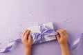 Christmas present stylish gift box in kids hands on lilac background. Creative Flat layout top view composition, mother day, saint