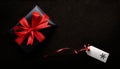 A Christmas present wrapped in black paper and red ribbon with a blank tag Royalty Free Stock Photo