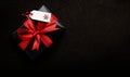 A Christmas present wrapped in black paper and red ribbon with a blank tag Royalty Free Stock Photo