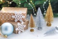 Christmas presents and gift boxes wrapped in kraft paper on a wooden table with gold and silver decorative Christmas trees, fir- Royalty Free Stock Photo