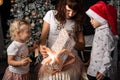 Mother with children unfolds a box with gifts.