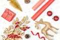 Christmas presents preparation - gift box, mistletoe, fircones,reindeer, christmas balls and paper in golden and red colors over Royalty Free Stock Photo