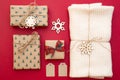 Christmas presents on red background. Kraft paper gift boxes, knitted scarf wrapped in twine, decorative snowflakes. Xmas and Happ