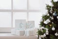 Christmas presents in white boxes on a window under a Christmas tree Royalty Free Stock Photo