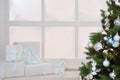 Christmas presents in white boxes on a window under a Christmas tree Royalty Free Stock Photo