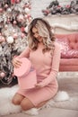 Christmas pretty girl portrait. Beautiful female present gift box. Happy Blonde woman in pink cloth with long hair sitting on fur Royalty Free Stock Photo