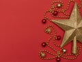 Christmas red background with golden star - the top of Christmas tree, golden beads and Christmas decoration. Royalty Free Stock Photo