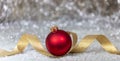 Christmas red ball, golden ribbon and snow, abstract bokeh lights background Royalty Free Stock Photo