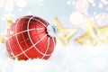 Christmas red ball on snow with golden stars on blue background Royalty Free Stock Photo