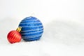 Christmas red and blue balls on abstract background Beautiful Christmas bauble decorations lie on the white fluffy snow Royalty Free Stock Photo