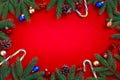 Christmas red decorations, candy cane, fir tree branches and xmas balls on red background Royalty Free Stock Photo