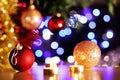 Christmas red and golden baubles with golden candles and tree sparking lights in background Royalty Free Stock Photo