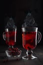 Christmas red hot mulled wine with berries and steam as Christmas tree shape in two transparent wine glasses on black wood table. Royalty Free Stock Photo