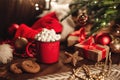 Christmas red mug with cocoa and marshmallows and cookies on a wooden table. New Year`s still life with a Christmas tree, a Santa Royalty Free Stock Photo