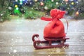 Christmas Red Sack With Gifts On Sled On A Wooden Background With Spruce Branches And Garlands.