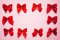 Christmas red satin bows frame, set of ribbons on pink background