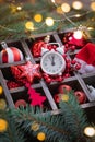 Christmas red and white glass toys, alarm clock, santa claus hat in the basket with fir tree branches background Royalty Free Stock Photo