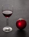 Christmas red wine. Wineglass and red xmas ornament bauble, black background, closeup view Royalty Free Stock Photo