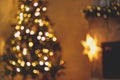 Christmas room golden bokeh. Blurred image of atmospheric christmas eve at fireplace. Defocused illuminated christmas tree and Royalty Free Stock Photo