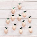 Christmas rustic background with string lights as pineapples golden colored. Festive decoration, New Year fairy garland Royalty Free Stock Photo