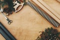 Christmas rustic flat lay. Stylish wrapping paper, wooden reindeer, pine branches and cones, scissors, thread on rural wooden