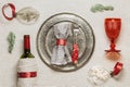 Christmas rustic table setting, bright tableware, red wine glass, plate, knife, fork, wine bottle, glass Christmas