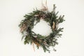 Christmas rustic wreath. Creative stylish rural christmas wreath with fir branches, berries, pine cones and herbs hanging on white