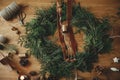 Christmas rustic wreath flat lay. Stylish christmas wreath with cedar branches, ribbon, vintage bells, pine cones, scissors on