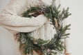 Christmas rustic wreath. Hipster girl in stylish white sweater holding rural christmas wreath with fir branches, berries, pine Royalty Free Stock Photo