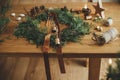 Christmas rustic wreath. Stylish christmas wreath with cedar branches, ribbon, vintage bells, pine cones, scissors on wooden table