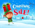 Christmas Sale! Little elf holds up gift present in Christmas snow scene winter landscape Royalty Free Stock Photo