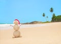 Christmas sandy snowman in santa hat at palm ocean beach Royalty Free Stock Photo