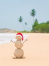 Christmas sandy snowman in santa hat at palm ocean beach Royalty Free Stock Photo