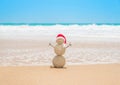 Christmas sandy snowman in santa hat at tropical beach