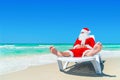 Christmas Santa Claus relax on sunlounger at ocean tropical beach
