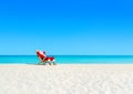 Christmas Santa Claus tan relaxing on sunlounger at sandy beach. Royalty Free Stock Photo