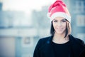 Christmas Santa hat outdoors woman smiling portrait . Smiling happy girl wearing her Santa hat with city urban background Royalty Free Stock Photo