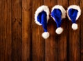 Christmas Santa Hats hanging on Wooden Board Background. Xmas Family Claus Cap over brown Grunge Wood Plank Wall. Xmas Holiday Royalty Free Stock Photo