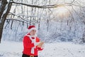 Christmas Santa reading letter near the Christmas nature background. Funny Santa in Santa hat read letter over winter