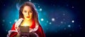 Christmas. Beauty brunette young woman in party costume opening gift box over holiday night background Royalty Free Stock Photo