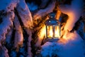 Christmas scene - an oil filled lantern burning bright with snow covered tree Royalty Free Stock Photo