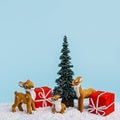 Christmas scene with red cup, pine tree, snow and small deer on pastel blue background. Creative Xmas or New Year festive concept. Royalty Free Stock Photo